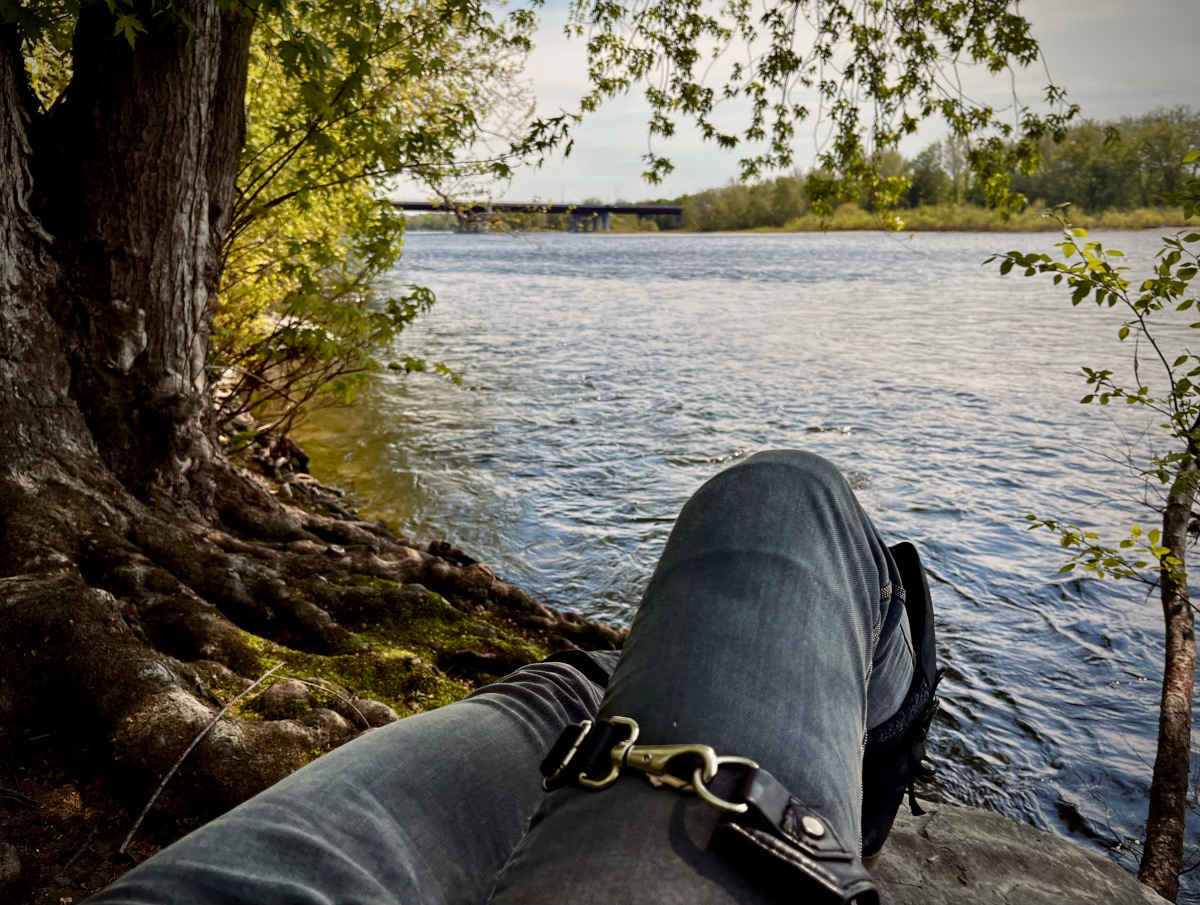 A photo of someone sitting by a river.